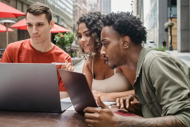 A group of diverse people smiling and learning together online, showcasing the inclusivity and community of online education.